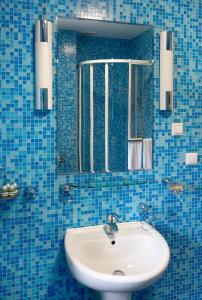 a blue tiled bathroom with a sink and a mirror at Rezydencja Prezydenta RP Zamek w Wiśle in Wisła