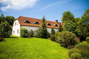 Biały dom z czerwonym dachem na zielonym trawniku w obiekcie Dwor Rychwald w mieście Rychwałd