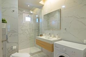 a white bathroom with a sink and a shower at Sonja Beachfront Apartments in Kato Daratso