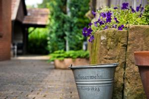 a bucket sitting next to a stone wall with flowers at Pension Alte Feuerwehr in Schüttorf +2 photos