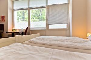 a bedroom with a white bed and two windows at Pension Alte Feuerwehr in Schüttorf