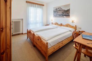 a bedroom with a wooden bed and a table at Hotel Al Larin in Cortina dʼAmpezzo