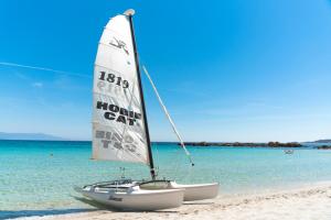 a sailboat sitting on a beach with the ocean at Hotel Dei Pini in Alghero
