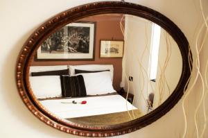 a mirror with a bed in a room at Ipazia House in Genoa