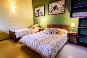 two beds in a bedroom with green walls at La Tosca Hostel in Puerto Madryn