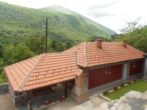 a house with a red roof with a mountain in the background at Vikendica RTANJ in Rtanj
