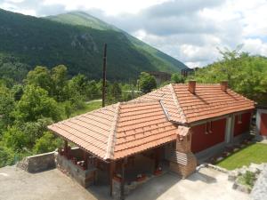 a house with a red roof with a mountain in the background at Vikendica RTANJ in Rtanj