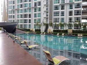 a swimming pool with chairs and a large building at Firina Home in Kuala Lumpur