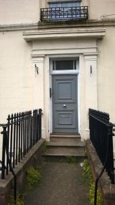 eine blaue Tür in einem weißen Gebäude mit einem Zaun in der Unterkunft Regents Street Studios in Leamington Spa