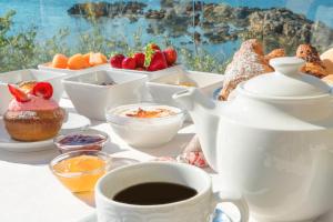 a table with cups of coffee and bowls of food at Hotel Dei Pini in Alghero