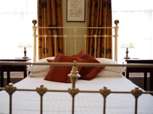 a bed with red and white pillows on it at The Coach House in Canterbury