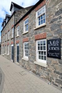 un bâtiment en pierre avec un panneau sur son côté dans l'établissement Me & Mrs Jones, à Portstewart