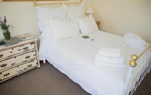 a white bed with white pillows and a night stand at De Kothuize 4 in Graaff-Reinet