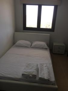 een bed met witte lakens en kussens in een kamer met een raam bij Kyperounta Apartment in Kyperounda