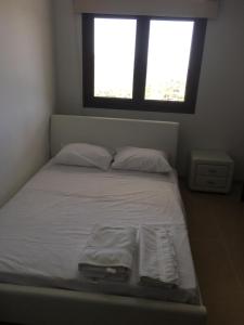 a bed with white sheets and pillows in a room with a window at Kyperounta Apartment in Kyperounda