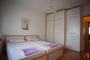 a bedroom with a bed with white cabinets and purple towels at Apartment Buzarovski in Skopje