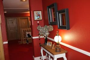 een hal met een rode muur met een tafel en een lamp bij Auberge Lorraine in Le Valtin