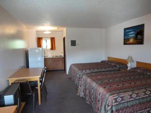 a hotel room with two beds and a desk at Spanish Fiesta Resort in Osoyoos