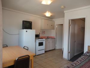 a small kitchen with a white refrigerator and a table at Falcon Resort in Osoyoos