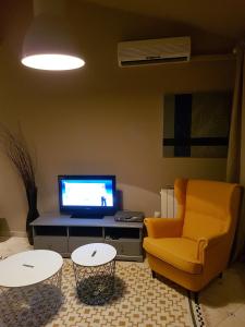 sala de estar con TV, silla y mesas en Apartments Villa Ban, en Rovinj