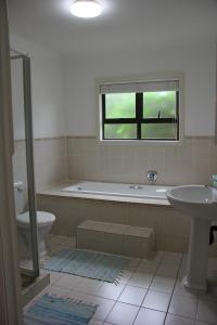 a bathroom with a tub and a toilet and a sink at Alfies House in Ponta Malangane