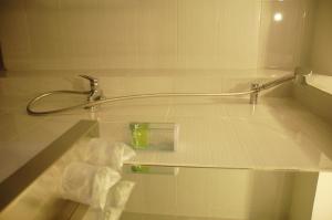 a bath tub with a shower head and a sink at Gandhi Inn in Medan