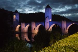 un castillo con un puente sobre un río por la noche en Le Balcon des Jasses en Espère