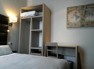 um quarto com uma cama, uma secretária e uma estante de livros em Hotel Napoléon em Cherbourg en Cotentin