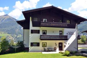 a large white house with a balcony and a table at Landhaus St Georg by AlpenTravel in Bad Gastein