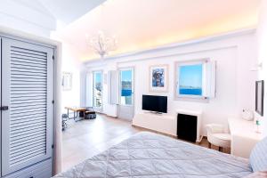 a white room with a bed and a tv at Santorini Secret Premium in Oia