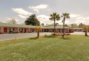a building with palm trees in front of a yard at Americas Best Value Inn-Savannah in Savannah