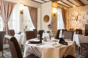 a restaurant with white tables and chairs and windows at Glenmoriston Arms Hotel in Invermoriston