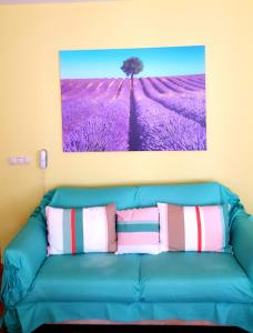 eine blaue Couch mit Kissen und ein Gemälde an der Wand in der Unterkunft Europroperties Iglika Apartments in Goldstrand