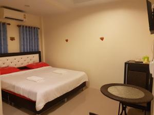 a bedroom with a bed with red pillows and a chair at Bann Lom Le Guest House in Hua Hin