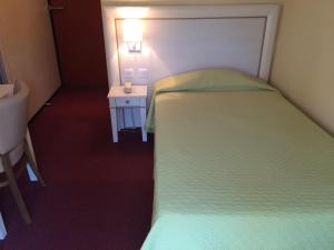 a small bedroom with a bed and a small table at Hotel Elysée in Lyon