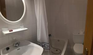 a bathroom with a sink and a toilet and a mirror at Pension Rosalia de Castro in Foz