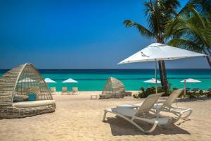 a beach with chairs and an umbrella and the ocean at Catalonia Royal La Romana Adults Only - All Inclusive in Bayahibe