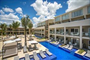 an image of the courtyard of a hotel with chairs and umbrellas at Catalonia Royal La Romana Adults Only - All Inclusive in Bayahibe