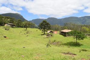 a field with houses and mountains in the background at Pousada Recanto Da Fortaleza in Pedra