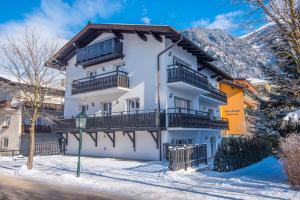 a white building with balconies on a snowy street at Haus Wasmer by AlpenTravel in Bad Hofgastein