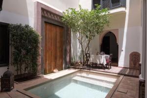 a pool in the courtyard of a house with a table at Dar Silsila in Marrakesh