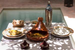 a table with plates of food and a bottle of wine at Dar Silsila in Marrakesh