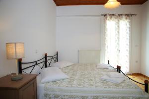a bedroom with a bed with a lamp and a window at Pine House with Sea View in Lefkada Town