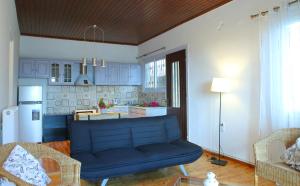 a living room with a blue couch and a kitchen at Pine House with Sea View in Lefkada Town