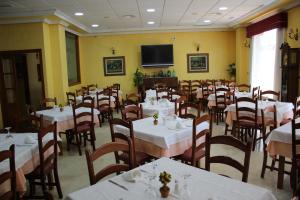 une salle à manger avec des tables, des chaises et une télévision dans l'établissement Hotel Albohera, à Santiago de la Ribera