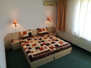 a bedroom with a bed with a quilt on it at Family Hotel Lipite in Tipchenitsa
