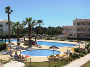 a beach with a pool, chairs, and a pool table at TURIM Estrela do Vau Hotel in Portimão
