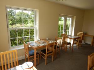 uma sala de jantar com mesas, cadeiras e janelas em Ghyll Beck House bed and breakfast em Leck