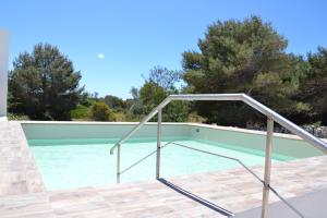 a swimming pool with a metal handrail next to a swimming pool at Plaia Resort in Favignana