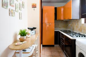a small kitchen with an orange refrigerator and a table at Le Scale Sul Barocco in Ragusa